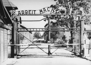 Brama do obozu koncentracyjnego w Auschwitz z napisem "Arbeit macht frei". Źródło: Wikimedia, domena publiczna.