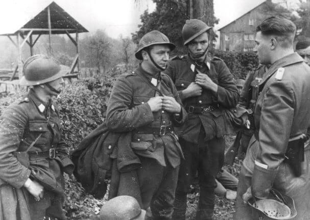 Niemiecki oficer przesłuchuje trzech belgijskich jeńców w maju 1940 roku. Źródło: NAC.