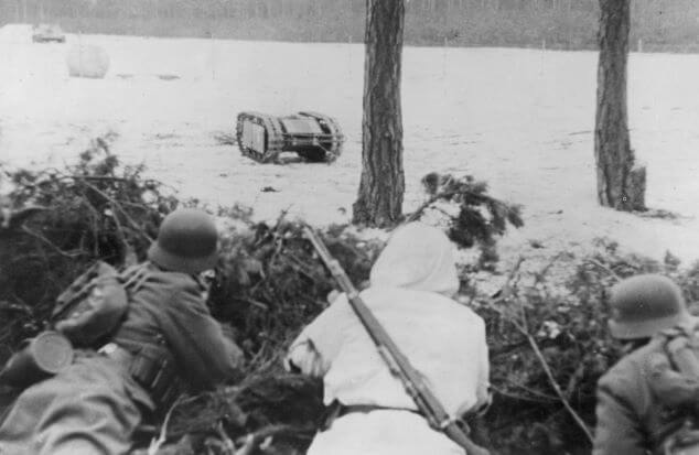 Mina samobieżna Goliat i obsługujący ją niemieccy żołnierze ukryci za sosnowymi gałęziami w marcu 1943 roku (NAC).