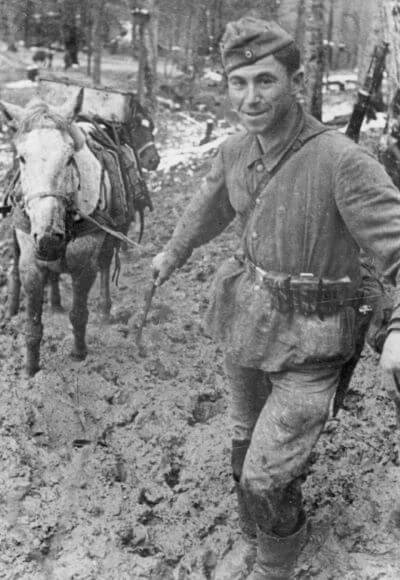 Żołnierz niemiecki z objuczonym mułem przedziera się przez błotnistą drogę na froncie wschodnim w grudniu 1942 roku. Źródło: NAC.
